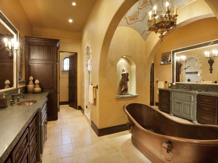 Spanskt badrum med kopparbadkar och väggar utan kakel och koloniala träskåp och ljuskronor