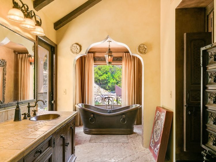 Marockanskt badrum i spansk stil med trä accenter och vintage speglar och ett fristående badkar