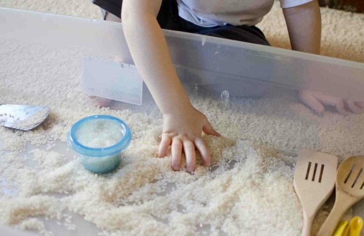 Lek med baby med produkter från köket - känna och lek med ris