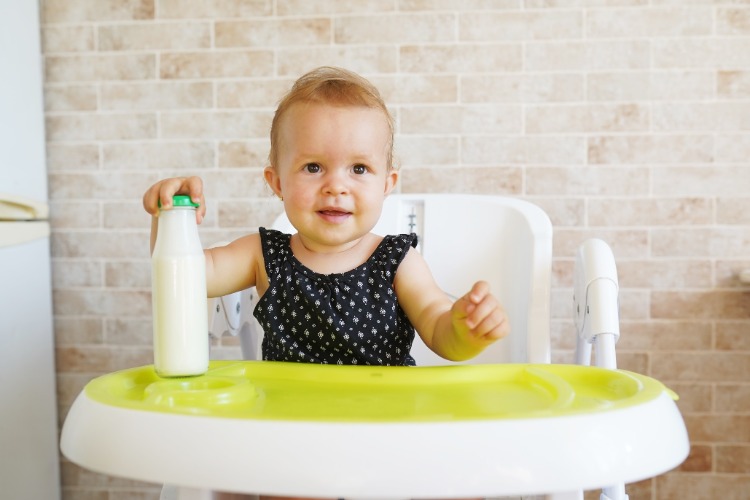 baby litet barn i stol med flaska med bröstmjölk