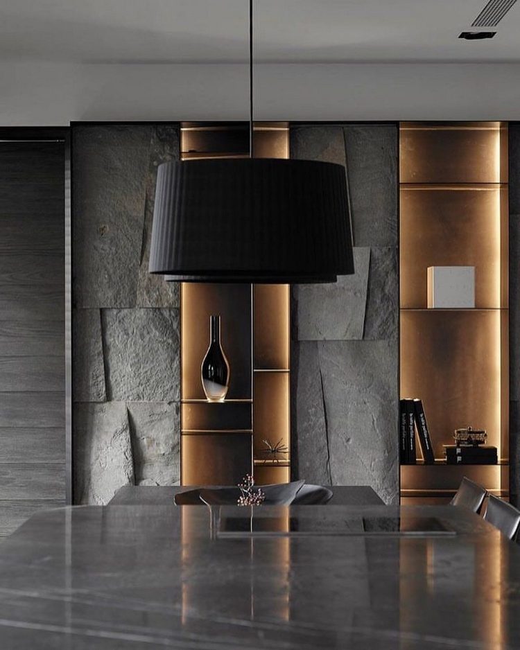 mörkgrå stenväggbeklädnad i kombination med en bordsskiva av marmor och golffärgade designelement