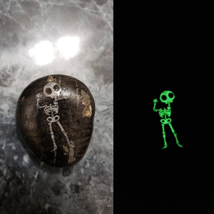 Måla skelettmotivet på stenen och spåra det med lysande färg