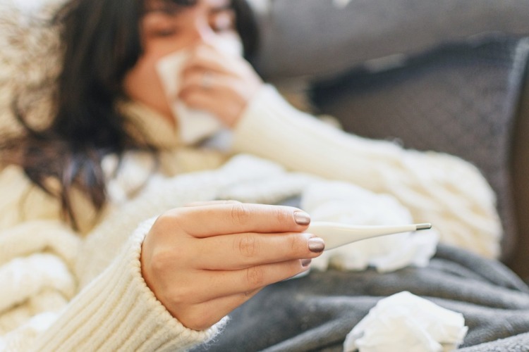 kvinnan ligger i sängen och kan inte känna igen symptom på grund av feber och rinnande näsa i covid 19