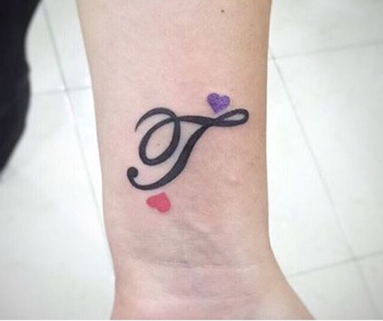 T -kirjain tatuointi pienillä sydämillä