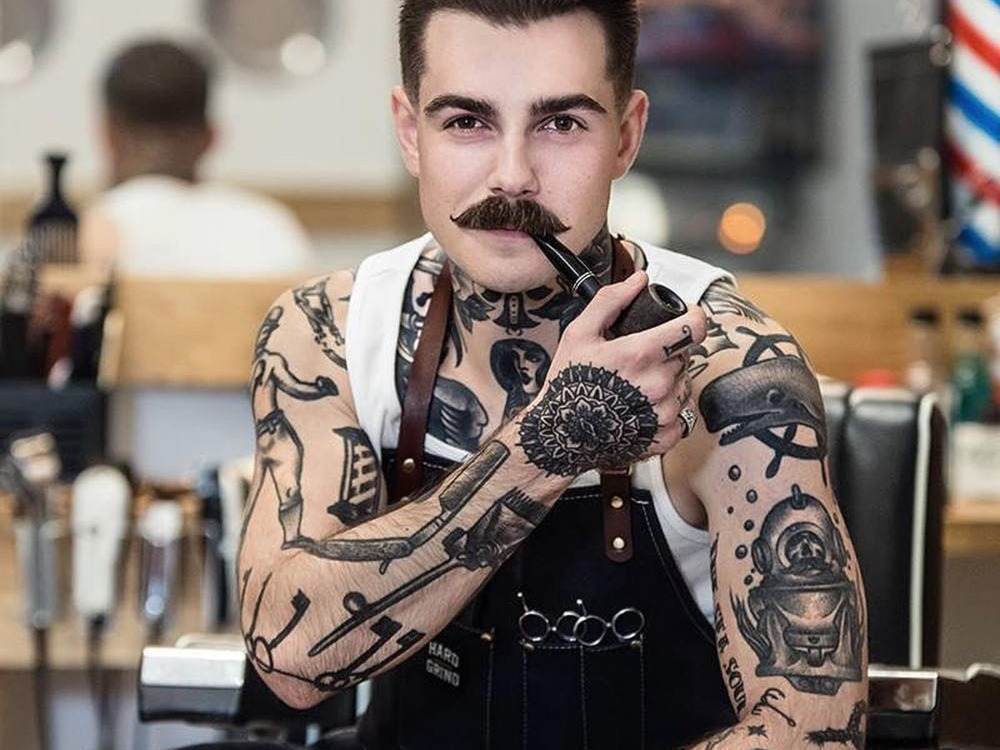 tatueringsarm man med mustasch och pipa poserar med sina konstverk på kroppen