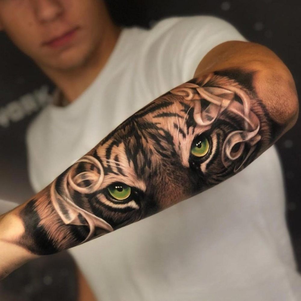 Tiger tatuering med gröna ögon på utsidan av mans arm