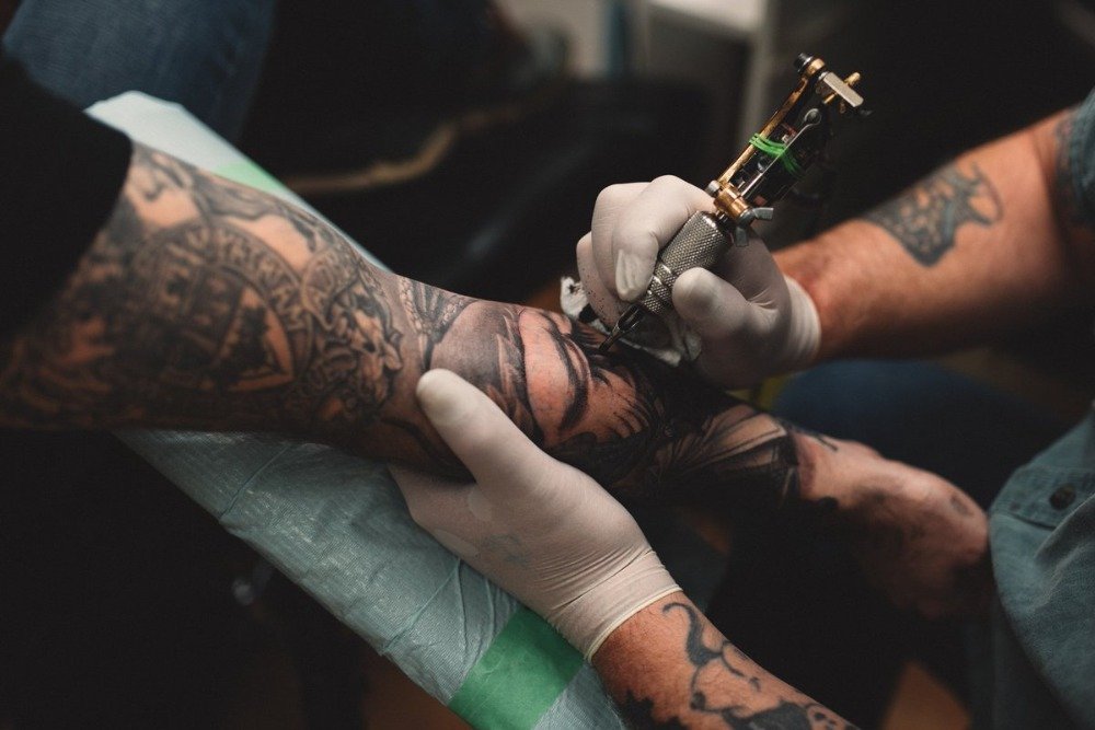 tatuerare med maskintatueringar människans arm i tatueringsstudion