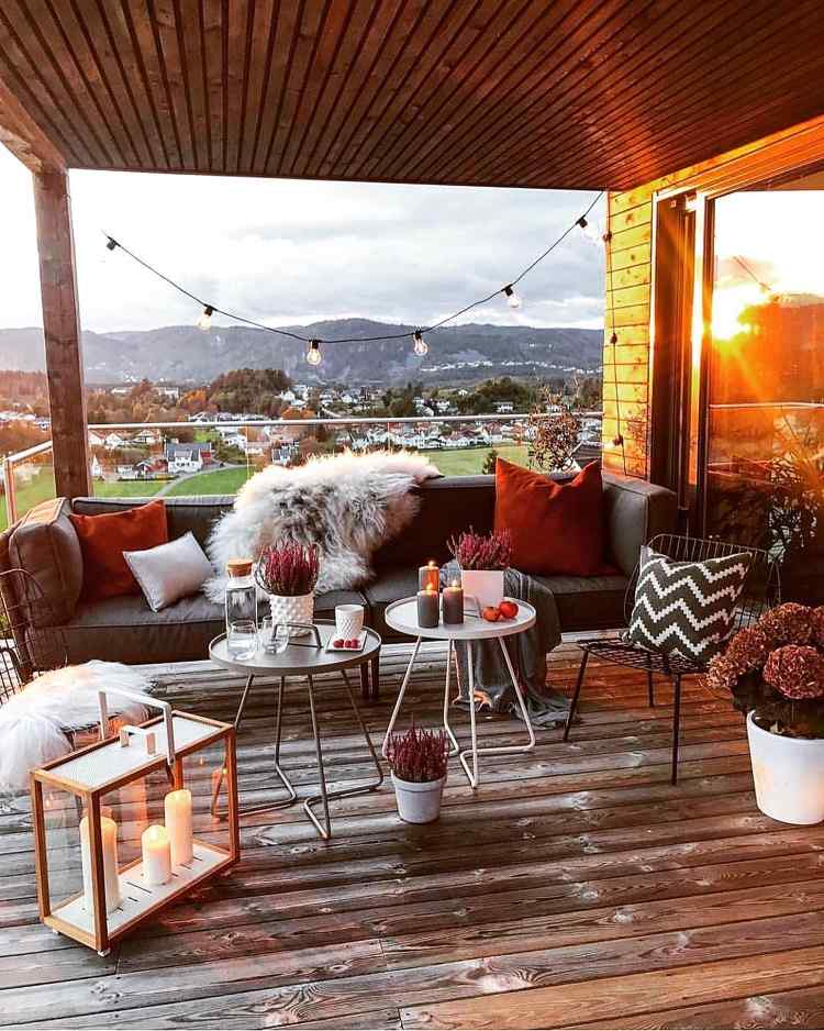 Dekorera terrassen på hösten med dekorativa kuddar i tegelrött och levande ljus