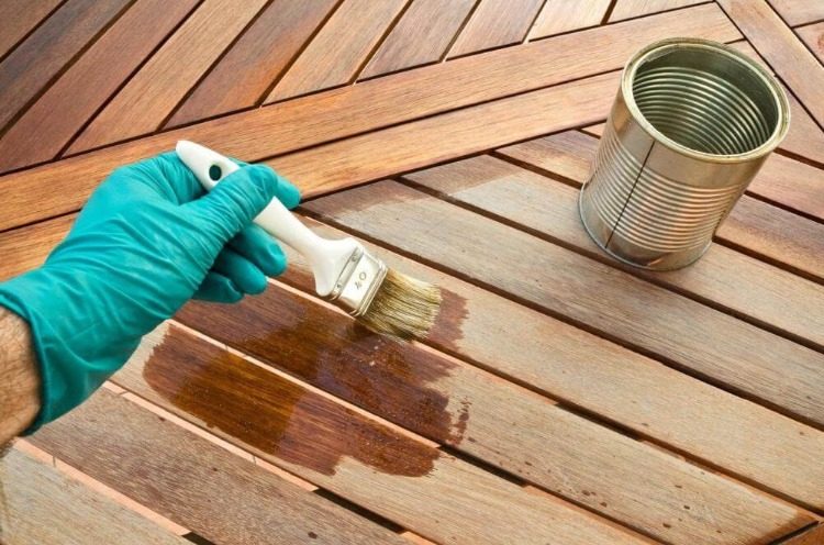Använd gummihandskar med en borste och förbered dig på att olja terrassen på våren eller på våren
