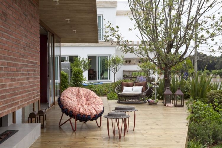 Terrass-design-fåtöljer-trädgård-kuddar-trägolv-ljuslyktor