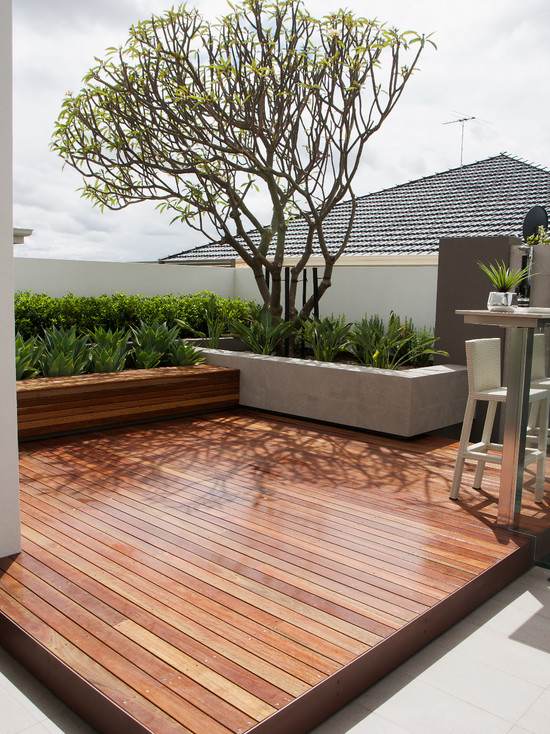terrass idéer trädgård trägolv betongvägg häckar växter träd