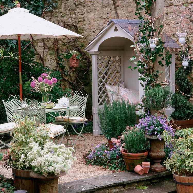 Romantisk trädgård i stugstil med en liten terrass och ett litet hus