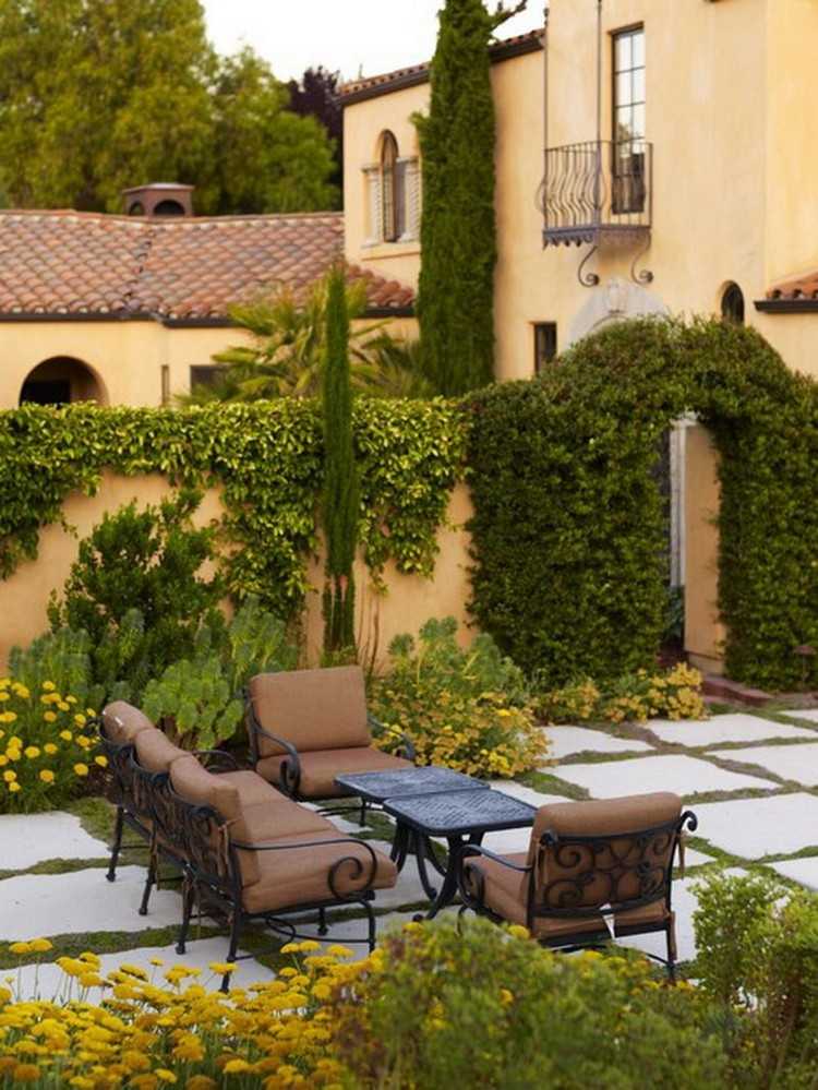 Toskansk terrass med möbler i smidesjärn och frodig växtlighet