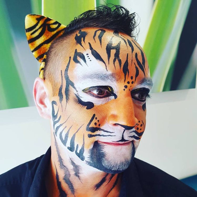 tiger applicerar smink lätt vuxen man karneval