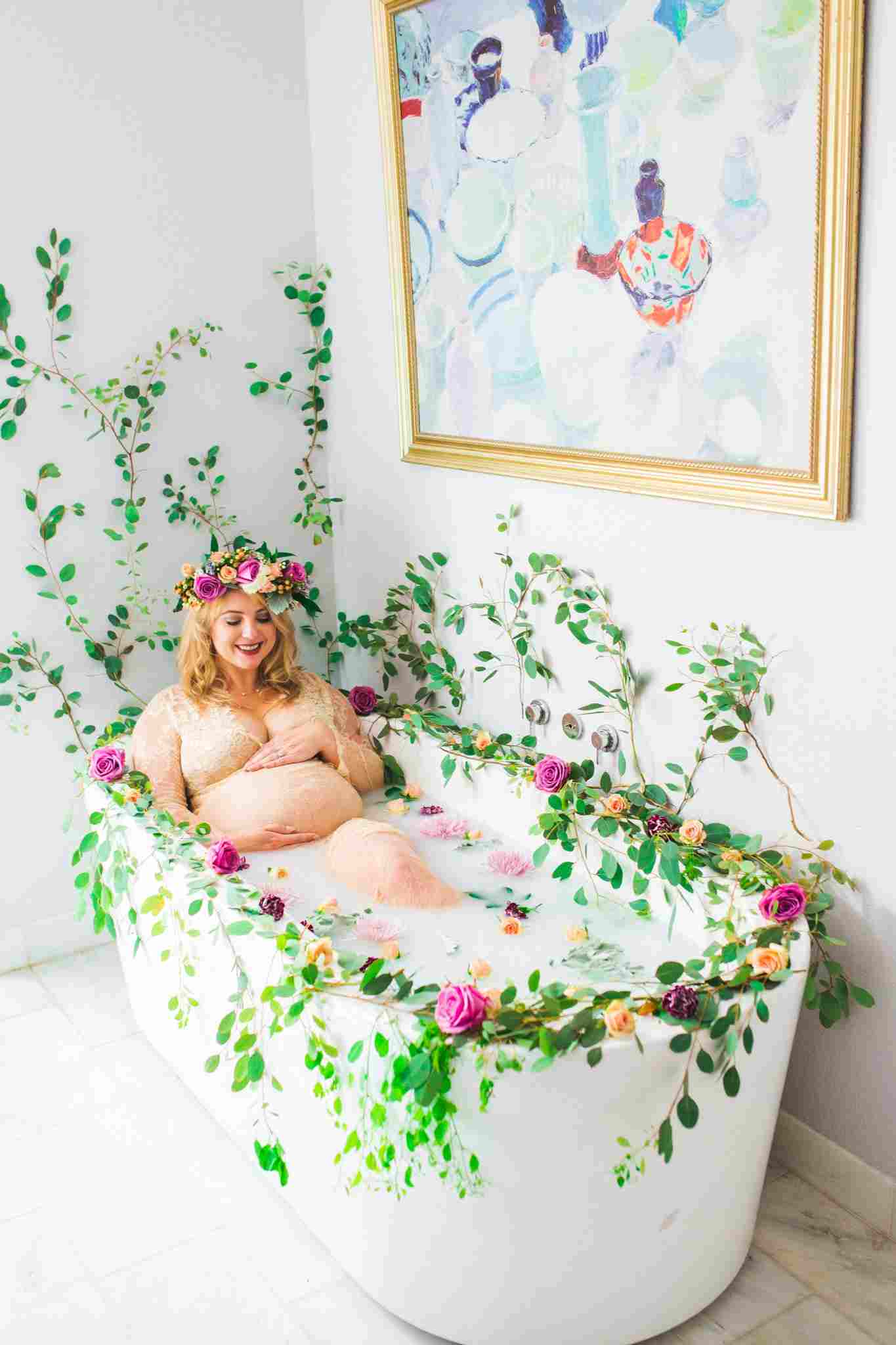 Romantisk skott i mjölkbadet med blommor och rankor under graviditeten