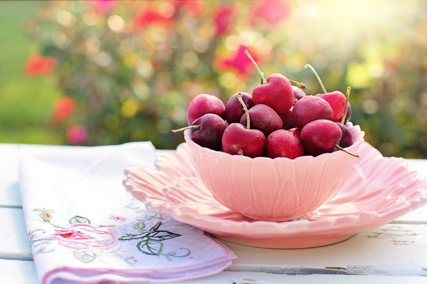 färska körsbär i rosa skål på ett bord en varm dag