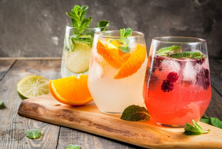 sommarcocktails utan alkohol med frukt och mousserande vatten, myntablad och en skiva apelsin