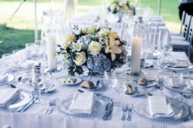 bordsdekorationer för bröllop blå accenter blomsterarrangemang ljus glasplattor