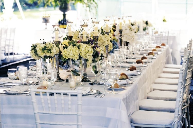 Bordsdekoration med hortensior-bröllop-bord-i mitten-ljusstaken-dekorerade-blommor-stolar-sittdynor-vit