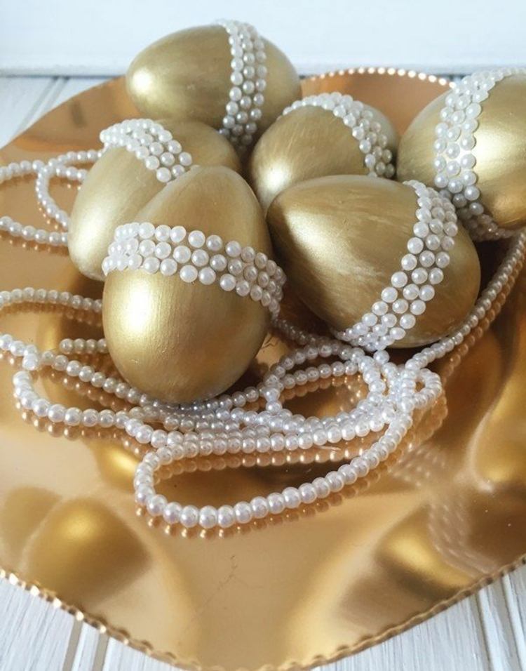 Gyllene ägg med vita pärlor på påskbordet