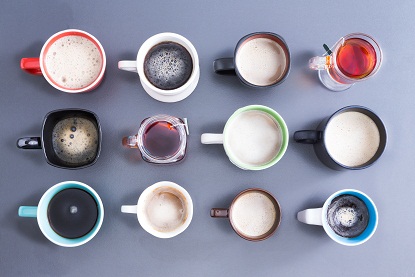 Εννοιολογική εικόνα που απεικονίζει την ώρα για την καθημερινή σας δόση καφεΐνης με μια γενική άποψη μιας τακτοποιημένης διάταξης δώδεκα διαφορετικών φλιτζανιών, κούπας και ποτηριών γεμάτων με ζεστό φρέσκο ​​τσάι και καφέ σε γκρι χρώμα