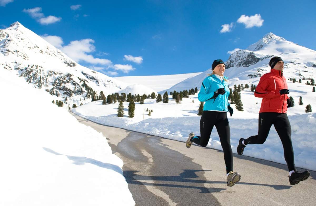 kvinna och man joggar mellan snö och berg på vintern