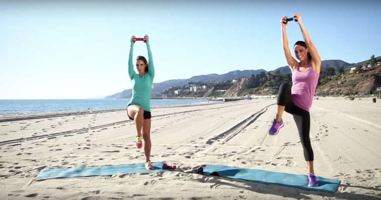 två kvinnor tränar på stranden med skumrullar och vikter