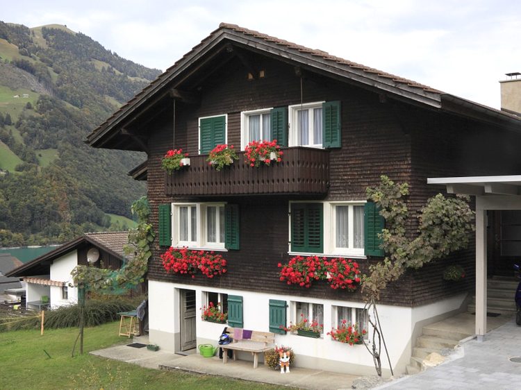 drömhus-schweiz-familj-två-våningar-röda pelargoner