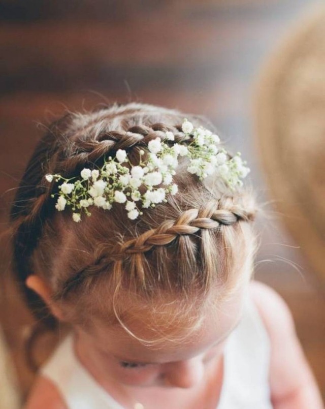 Flätat hår smyckat med blommor på toppen av huvudet