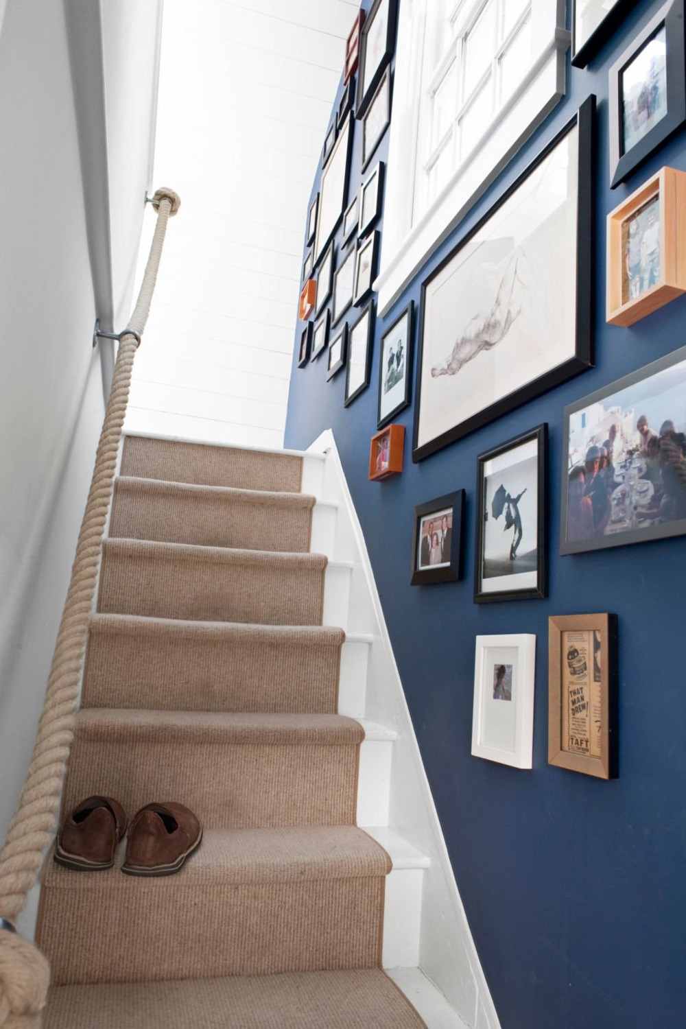 ljusbrun mattlöpare på trappan med trappvägg i blått dekorerad med foton