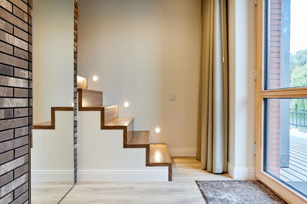 inbyggd led trappbelysning och trappsteg av trä i ett ljust rum med en stor spegel på en tegelvägg