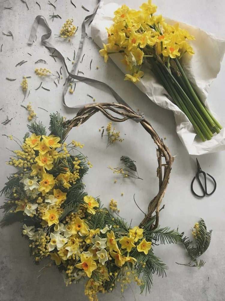 Vacker vårdekoration i gult med påskklockor och mimosa