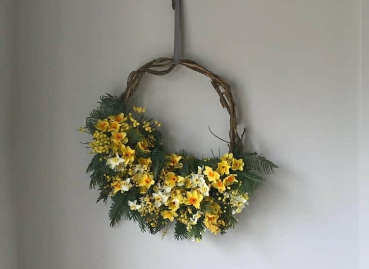 Vårdörrkransar av naturmaterial i gult - påskliljor, mimosa och trumpinnar