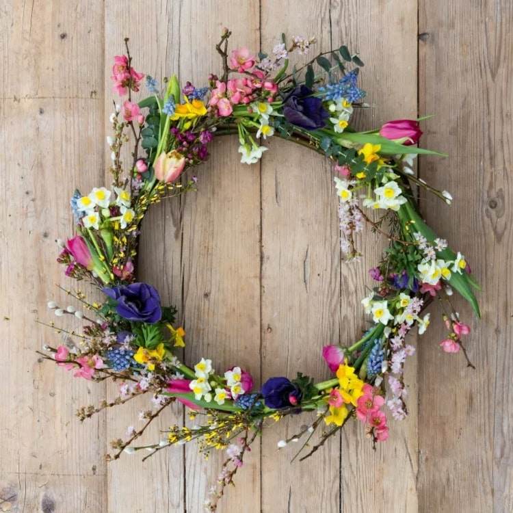 Färgglada dörrkransar för våren gjorda av naturmaterial - färska blommor och grenar med blommor