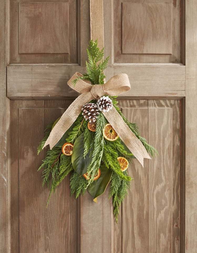 Gör dörrpynt till jul av naturmaterial med cypressgrenar och apelsiner