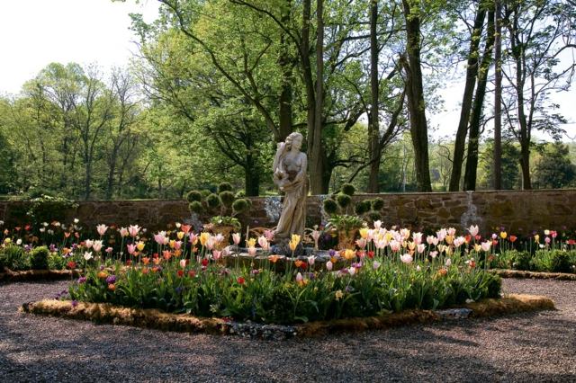 Tulpaner rabatt stensten staty trädgårdsarbete