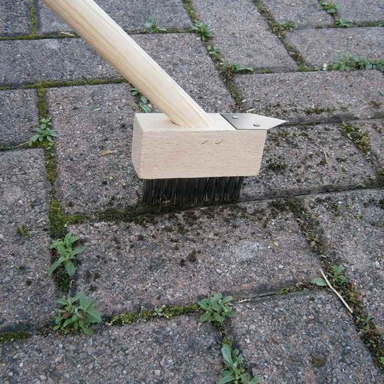 Använd en ogräsborste för att ta bort ogräs från lederna på gatsten