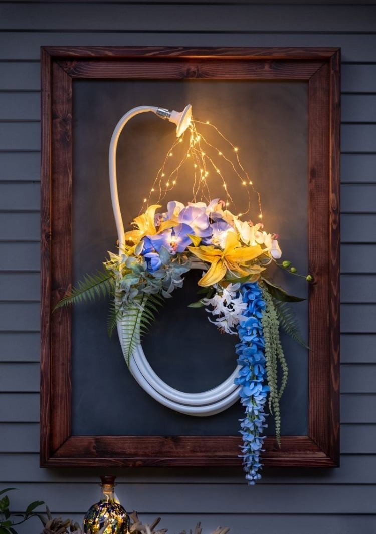 kedjeljus upplyst dörrkrans med vacker dekoration av blommor och trädgårdsslang