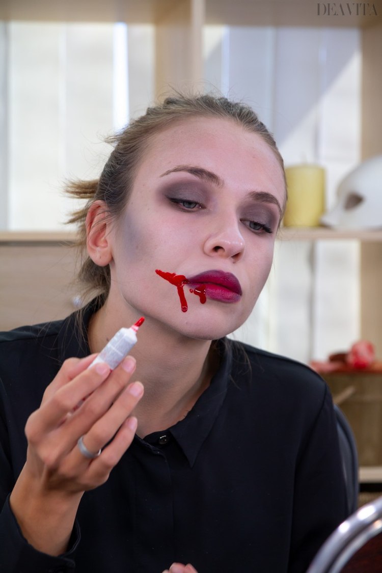 Vampyrsmink applicerar falskt blod i munvinklarna
