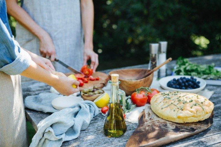 Skär tomater och andra grönsaker på bordet, kombinera med tunnbröd och olivolja för en vegansk kost