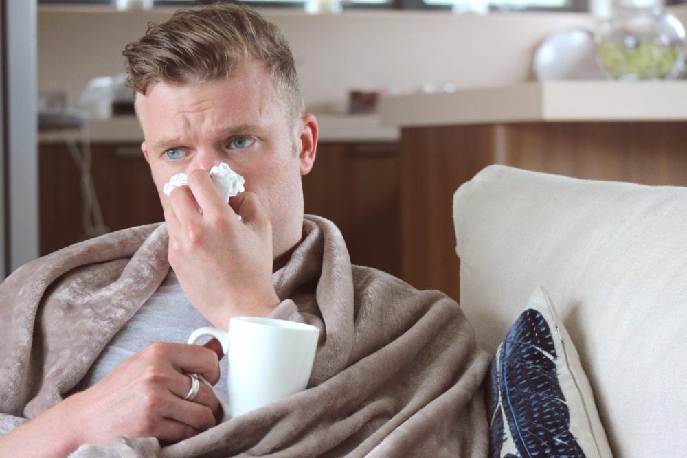 rengör näsan med en filt i soffan och drick te