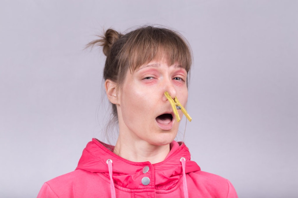 kvinna med rosa jacka och gula klädnypor blockerade på näsan