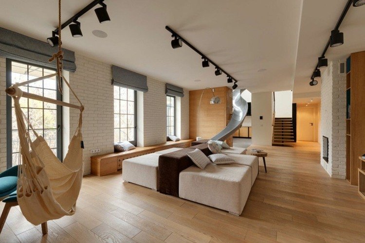 vardagsrum-hängande stol-modul-soffa-kuddar-glid-trappor-laminatgolv-vit tegel vägg-öppen spis