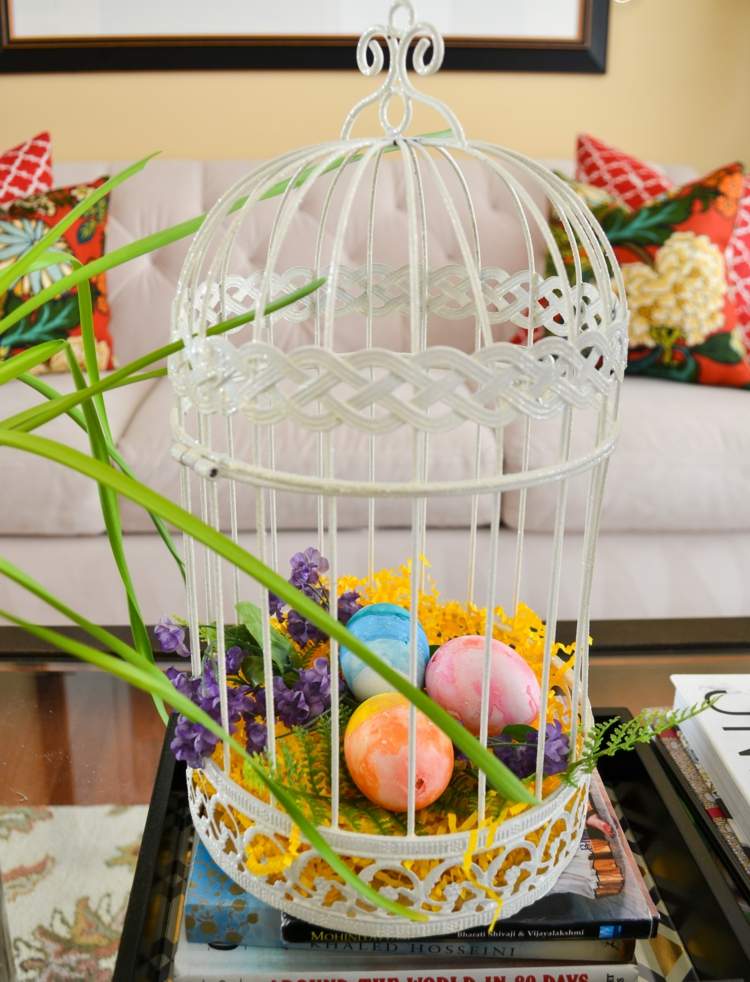 Dekorera fågelburen på våren och påsken med färgglada påskägg i påskkorgen