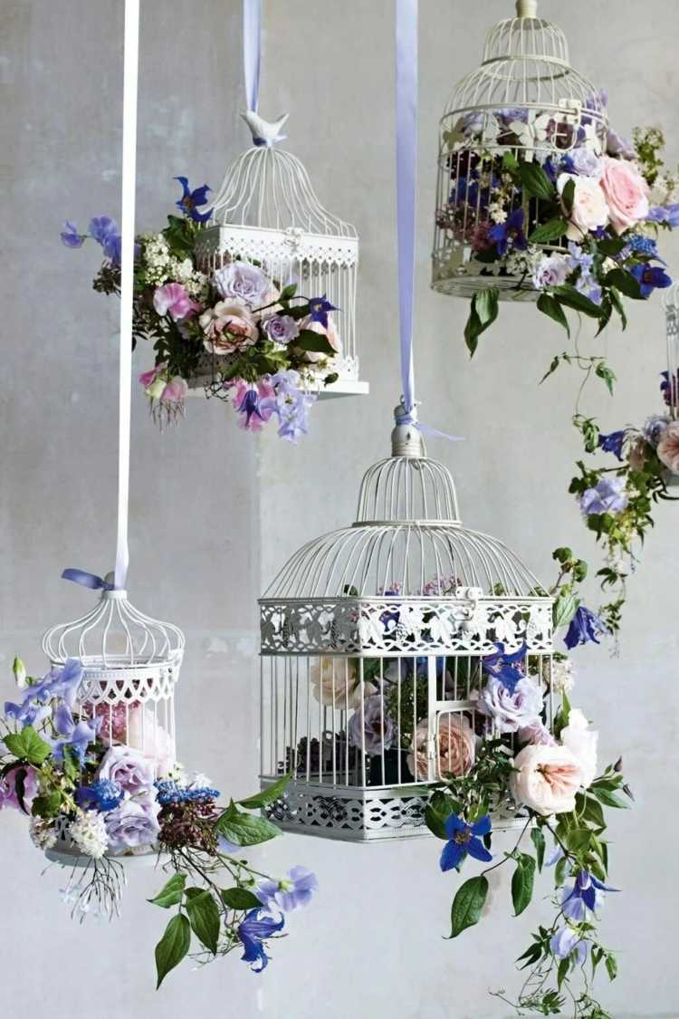 Dekorera den hängande fågelburen på våren med vackra blommor i lila och rosa