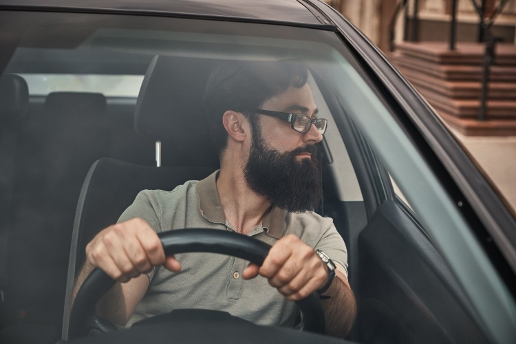 Modern snygg man med skägg och glasögon i bilen
