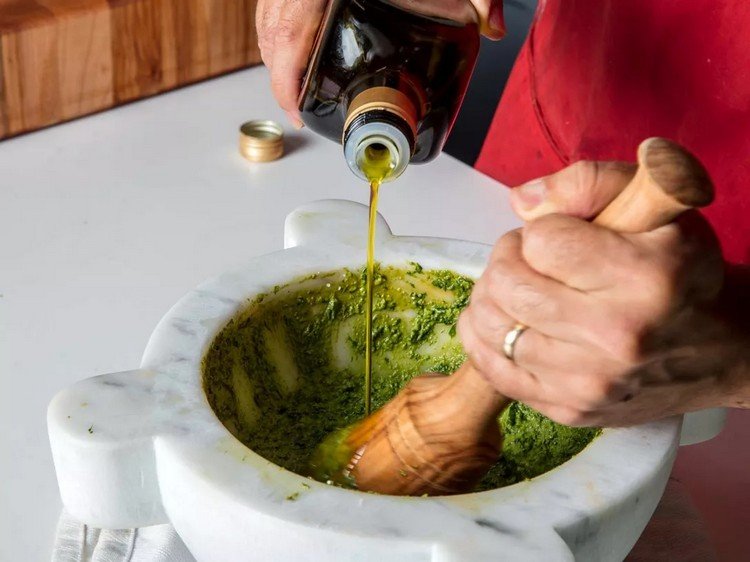 Tillsätt olivolja till basilikan i en mortel