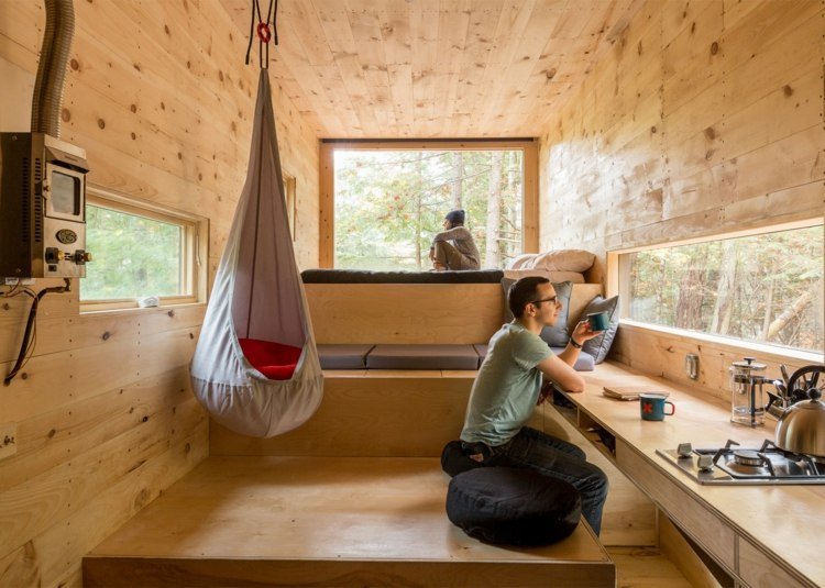 interiör skogshus gjord av trä väggpanel sittdynor hängande stol