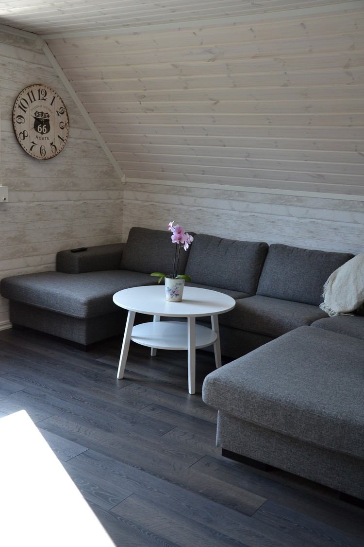 väggpanel-trä-vitt-hus på landet-vardagsrum-sluttande tak-grå-hörn-soffa-vitt-runt-soffbord