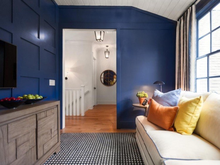 väggbeklädnad-trä-inuti-blå-soffa-vita-kuddar-orange-byrå-tv